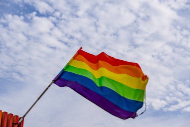 Mavi gökyüzüne karşı rüzgarda dalgalanan gökkuşağı bayrağı. LGBTIQ gururu Rüzgarda sallanan tuhaf bayrak