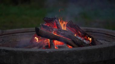Kamp ateşinde kıvılcımlar ve dumanlarla yanan odunların yavaş çekimleri.
