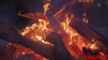 Kamp ateşinde kıvılcımlar ve dumanlarla yanan odunların yavaş çekimleri.