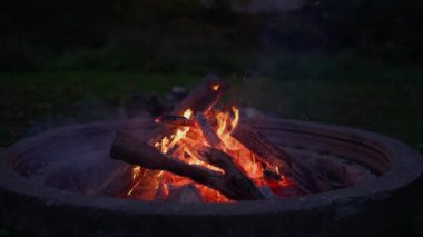 Kamp ateşinde kıvılcımlar ve dumanlarla yanan odunların yavaş çekimleri.