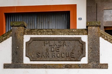 Plaza de Samroue yazan bir tabela. Tabela taş bir duvarda. kanaryalar