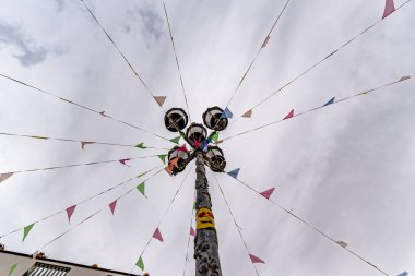 Üzerinde bir sürü bayrak sallanan uzun bir direk. Bayraklar farklı renk ve boyutlarda. Kutup bulutlu bir gökyüzü ile çevrilidir.