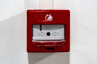 Solunda beyaz ok olan kırmızı bir yangın alarmı. Alarm duvarda.