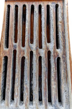 Bir sürü deliği olan ahşap bir ızgara. Delikler şebeke şeklinde aralıklı ve ahşap eski ve yıpranmış görünüyor. Manzara kasvetli ve nostaljik.