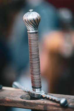 Gümüş saplı ve altın uçlu bir kılıç. Kılıç ahşap bir masaya dayanıyor.