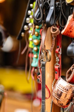 Askıda asılı deri kayışlar ve tokalar koleksiyonu. Kayışlar farklı renk ve boyutlarda ve tokalar da farklı şekil ve boyutlarda.