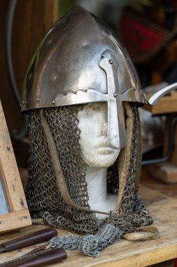 A helmet with a chain around it is on a table. The helmet is old and has a metal cross on it clipart