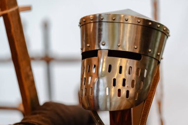 Metal yüzlü ve kayışlı bir şövalye miğferi. Miğfer gümüş renginde ve siyah beyaz bir tasarımı var.