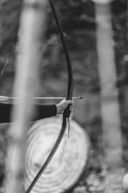 Bir adam elinde yay ve ok tutuyor, ve görüntüde bir kararlılık ve odaklanma havası var.