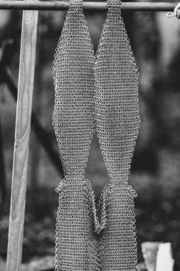 Üzerinde şablon olan bir metal parçası ahşap bir direğe asılı. Metal bükülmüş ve çok fazla detaya sahip. Bu da ona eşsiz ve ilginç bir görünüm veriyor. Görüntü biraz karamsar.