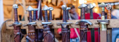 Bir sıra kılıç ahşap bir askıda sergilenir. Kılıçlar çeşitli boyutlarda ve stillerde ve düzenli ve düzenli bir şekilde düzenlenmişlerdir. Tarih ve gelenek kavramı