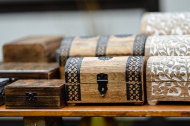 Siyah saplı ahşap bir sandık diğer ahşap sandıkların yanında bir masada oturur. Sandıkların hepsi farklı boyutlarda ve şekillerde, ama hepsinin tasarımı aynı. Sahne kırsal bir görüntü veriyor.