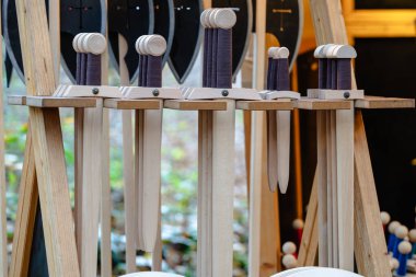 Siyah arka planı olan tahta bir kılıç gösterisi. Kılıçlar sıra sıra dizilmiş ve farklı boyutlarda.