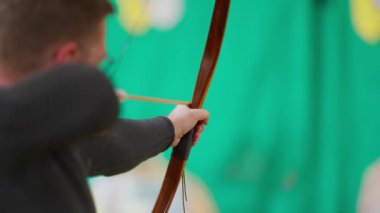 Bir adam ok ve yay tutuyor ve ateş etmek üzere. Adam atışını yapmaya hazırlanırken odaklanma ve kararlılık kavramı