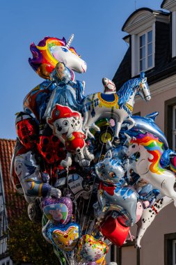 Üzerinde tek boynuzlu at ve yunus olan bir sürü balon. Balonlar bir demet içinde ve bir direğe asılı.