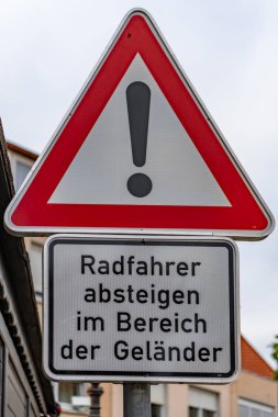 Üzerinde ünlem işareti olan kırmızı ve beyaz bir tabela. İşaret Almanca ve diyor ki 