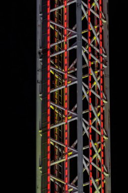 Üzerinde kırmızı ve sarı ışıklar olan uzun bir bina. Işıklar zikzak şeklinde dizilmiş.