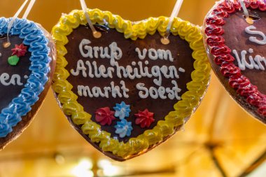 Üzerinde şekerleme ve yazı olan üç kalp şeklinde kurabiye. Yazı Almanca ve diyor ki 