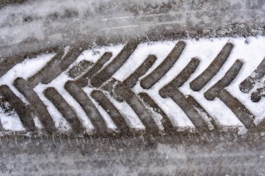 Görüntüde karda bir lastik izi gösteriliyor. Lastik izleri tekerlek tellerine benzeyen bir dizi çizgiden oluşuyor. Hareket ve eylem kavramı, sanki birisi karda araba kullanmış gibi.