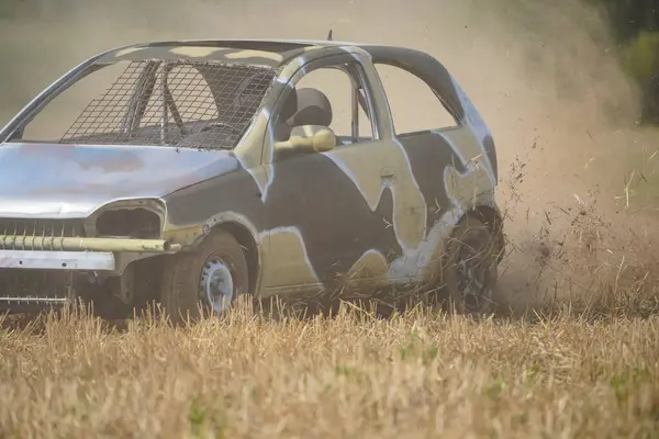 Bir araba uzun otların arasından geçiyor. Araba çamur ve çamurla kaplı ve şu anda yok edilme aşamasında.