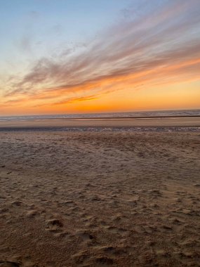 Gün batımında güzel bulut desenleri Sahilde ayak izleriyle