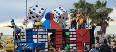 Palmiye ağaçları ve denizin arka planında renkli bir festival alayı.