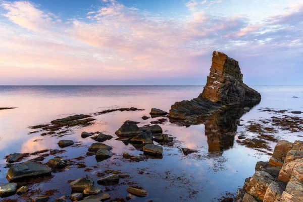 stock image Colorful sunset over the Black Sea coast of Bulgaria with a sea stack and rocks in the calm water