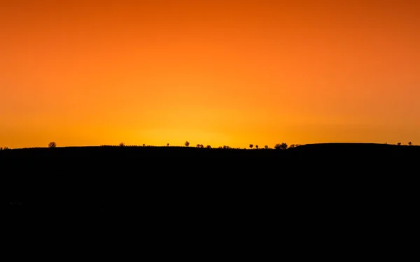 Een Warme Zonsondergang Een Bergkam Met Bomen Silhouet Heuvels Van — Stockfoto