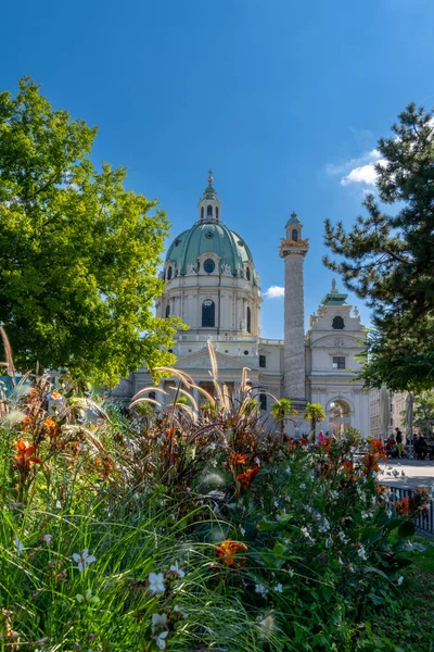 ウィーン オーストリア 2022年9月22日 ウィーンのダウンタウンにあるカルル教会の垂直方向の景色と前景にカラフルな花 — ストック写真