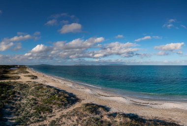 Tenha ve uzun kumlu bir sahilin turkuaz okyanus suyuyla hava manzarası.