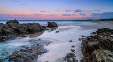 La Pelosa Sahili 'nin beyaz kumsal ve turkuaz sularının üzerinde renkli bir gün batımı.