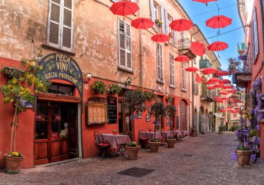 Luino, İtalya - 16 Mart 2023: Eski şehir merkezi Luino 'da küçük dükkanları ve renkli süslemeleri olan parke taşı caddesi