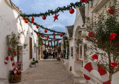 Alberobello, İtalya - 2 Aralık 2023: Trulli evleri, kulübeleri ve renkli Noel süslemeleri ile Alberobello 'nun Rione Monti Bölgesi' nde sokak