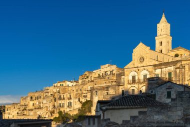 Matera, Italy - 26 November, 2023: view of the historic Maratea Cathedral and the stone houses of the Sassi di Matera in warm golden evening light clipart