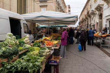 Syracuse, İtalya - 28 Aralık 2023: Syracuse pazarındaki müşterilere meyve ve sebze satan manav