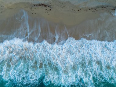 Tropea 'daki altın rengi Rotonda Sahili' nin tepesinde turkuaz su ve dalgalar kıyıya vuruyor.