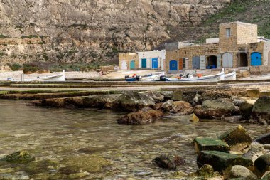 Dwejra, Malta - 19 Aralık 2023: Malta 'daki Gozo Adası' ndaki İç Deniz lagünündeki renkli balıkçı köyü ve tekneleri