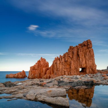 Arbatax 'ın kırmızı kayalarının ön plandaki gelgit havuzlarındaki yansımaları.