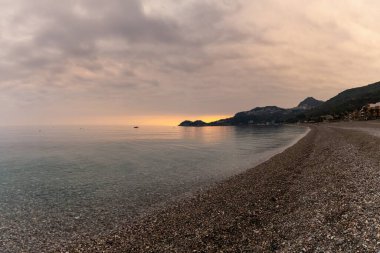 Sicilya 'da günbatımında Letojanni' de taş çakıl taşı plajı ve temiz su manzarası.
