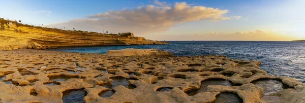 A panorama landscape view of the tidal pools and cliffs at Il-Hofra z-Zghira Bay in Malta
