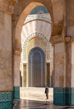 Casablanca, Fas - 29 Mart 2024: Kazablanka 'daki Hasan II Camii' nin kemerli kapıları ve kapıları altında konuklarını bekleyen yerel tur rehberi.