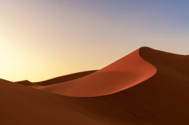 A view of the sand dunes at Erg Chebbi in Morocco in warm evening light clipart