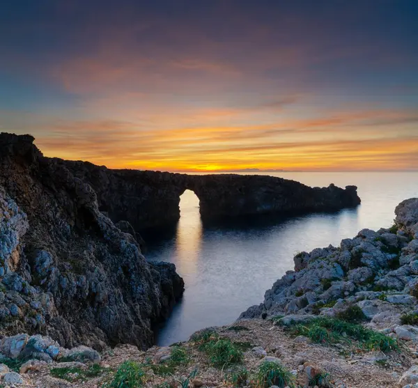 stock image A view of the landmark stone arch of Pont d'en Gil on Menorca Island just after sunset
