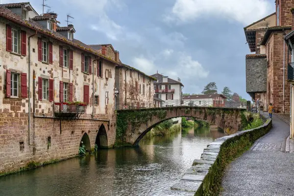 stock image Saint-Jean-Pied-de-Port, France - 17 April, 2024: view of the old town of Saint-Jean-Pied-de-Port with the stone bridge over the Nive River