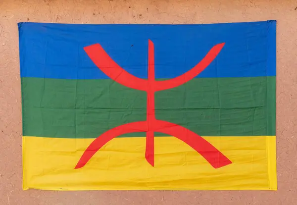 stock image A close-up view of a Berber flag with the free man symbol hanging from an adobe wall in the Moroccan desert