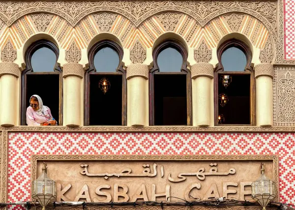 stock image Marrakesh, Morocco - 23 March, 2024: Muslim woman observing city life and looking out the upstairs window of the Kasbah Caf ein downtown Marrakesh