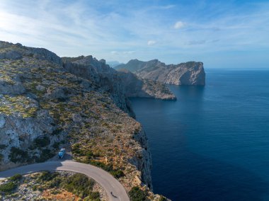 Kuzey Mallorca 'daki Cap de Formentor' a giden virajlı dağ yolunda bir bisiklet ve karavan.