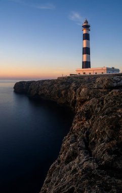 Gündoğumundan hemen sonra Menorca Adası 'ndaki Cap d' Artrutx deniz fenerinin dikey görüntüsü