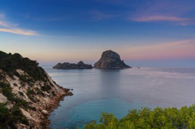 Es Vedra adasının manzarası ve gün doğumunda İbiza kıyılarında kayalar.