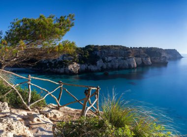 Güney Menorca 'daki cennet gibi Cala Macarella manzarası. Önünde bir yürüyüş yolu var.